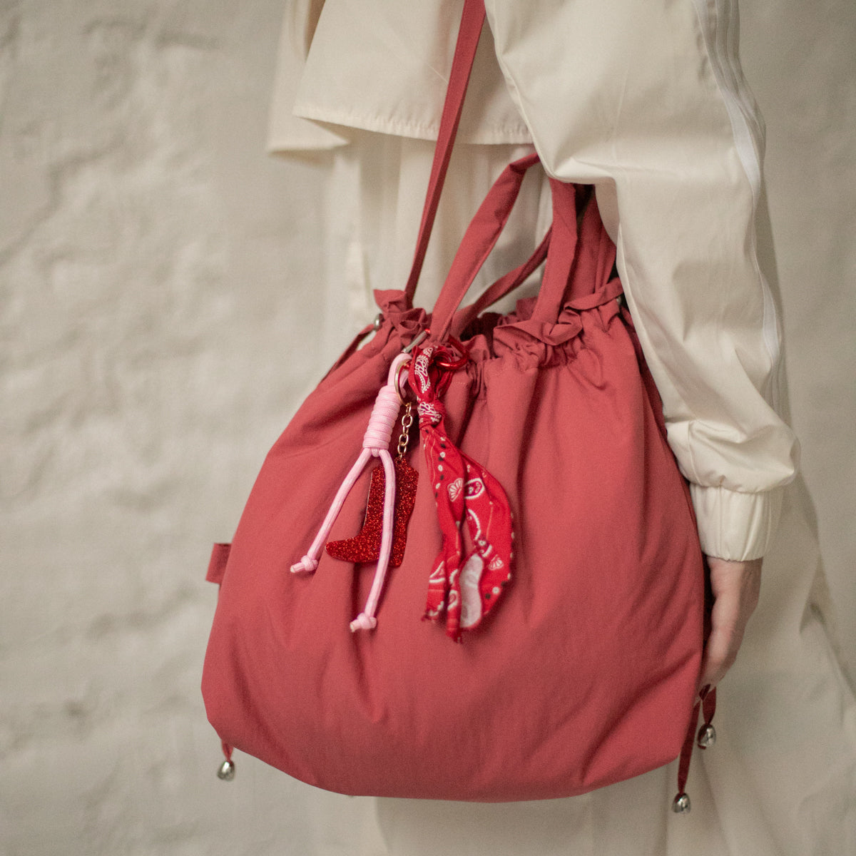 Sac bourse Manhattan rouge corail taille M porté à l'épaule, liens coulissants ornés d'un foulard – patron de couture Ikatee