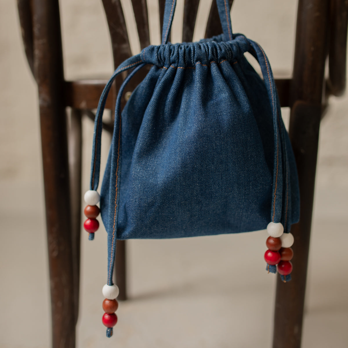 Détail du sac bourse Manhattan en denim bleu, liens coulissants ornés de perles en bois – patron de couture Ikatee