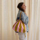 Sac bourse Manhattan à larges rayures rose et kaki porté à l'épaule – patron de couture Ikatee