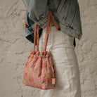Sac bourse Manhattan en tissu matelassé fleuri rose porté à la main – patron de couture Ikatee