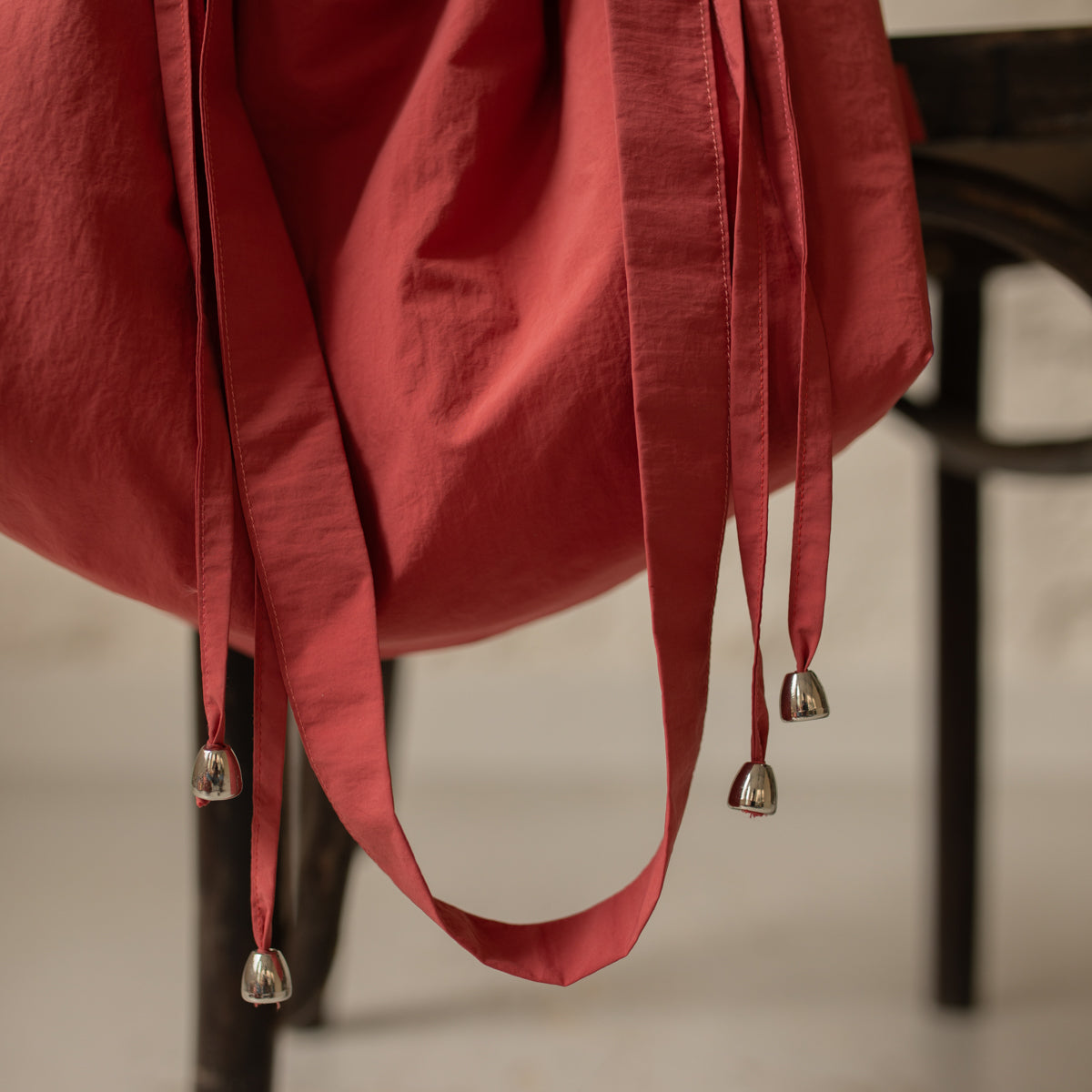 Détail de la bandoulière et des liens coulissants d'un sac bourse Manhattan rouge corail – patron de couture Ikatee