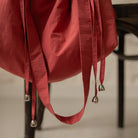 Détail de la bandoulière et des liens coulissants d'un sac bourse Manhattan rouge corail – patron de couture Ikatee